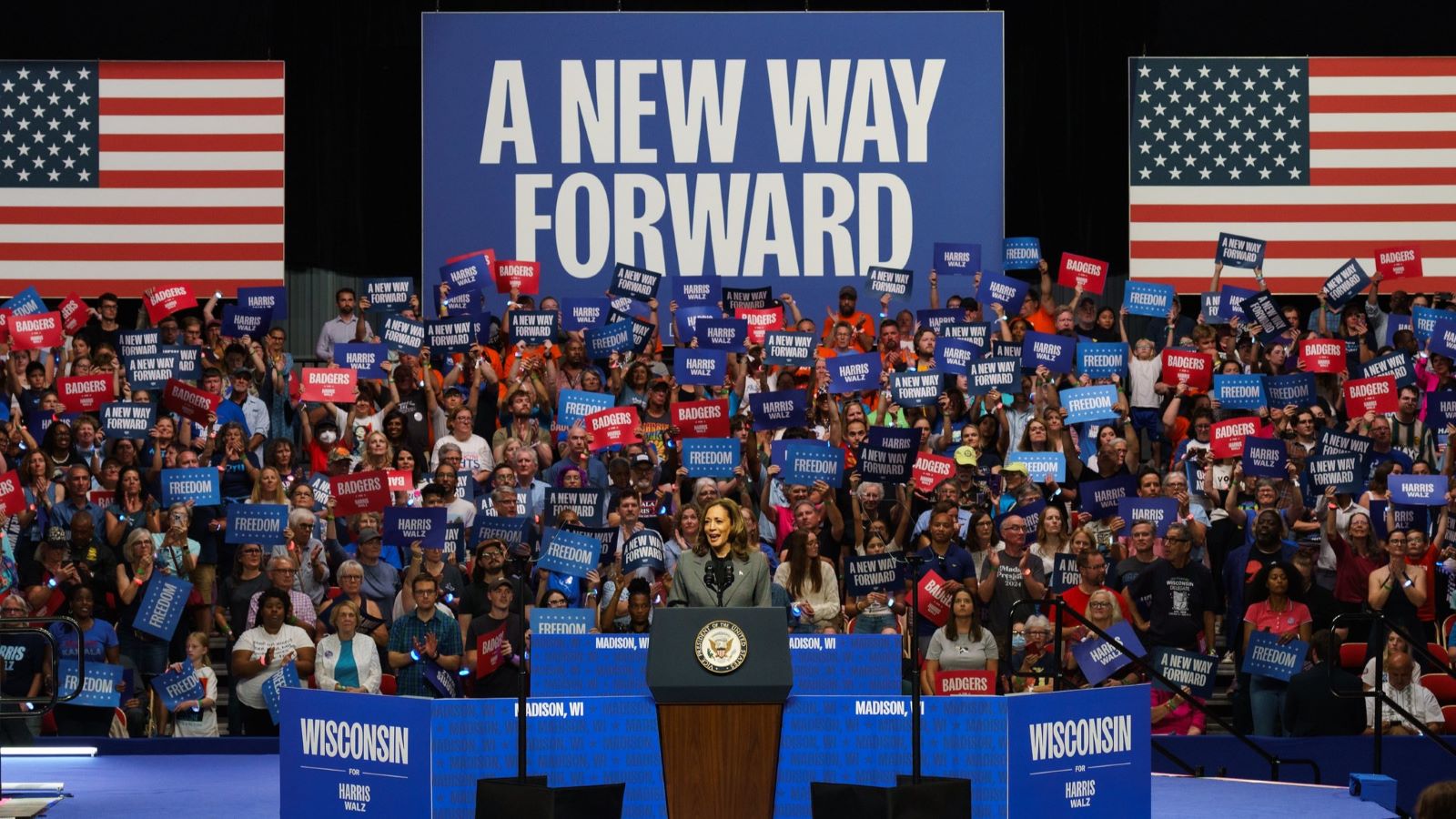 Harris speaking at the podium of a crowded campaign rally in Wisconsin.