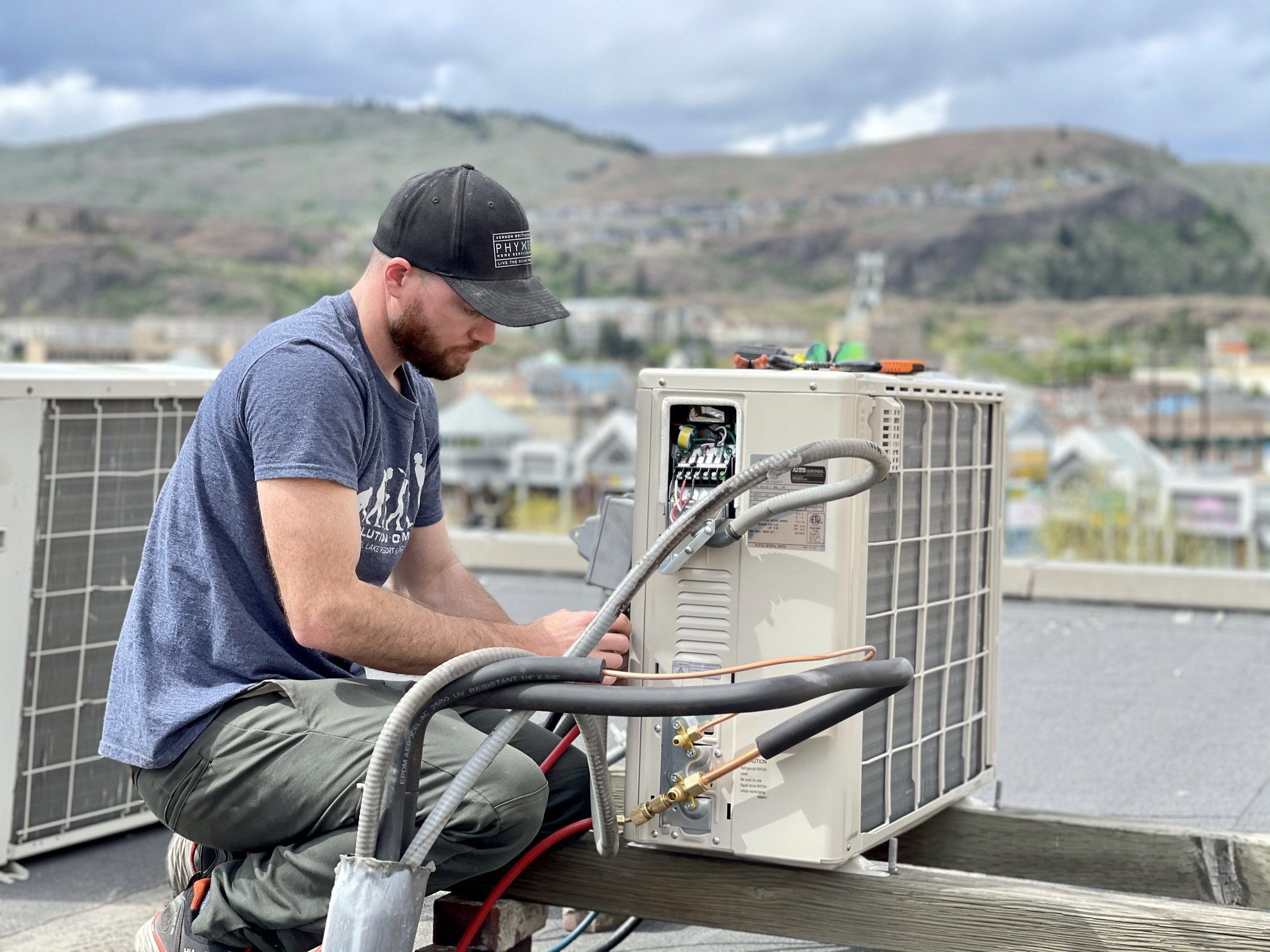 A man installs a ductless heat pump on a roof © 2021 Vernon Air Conditioning/Flickr CC BY 4.0