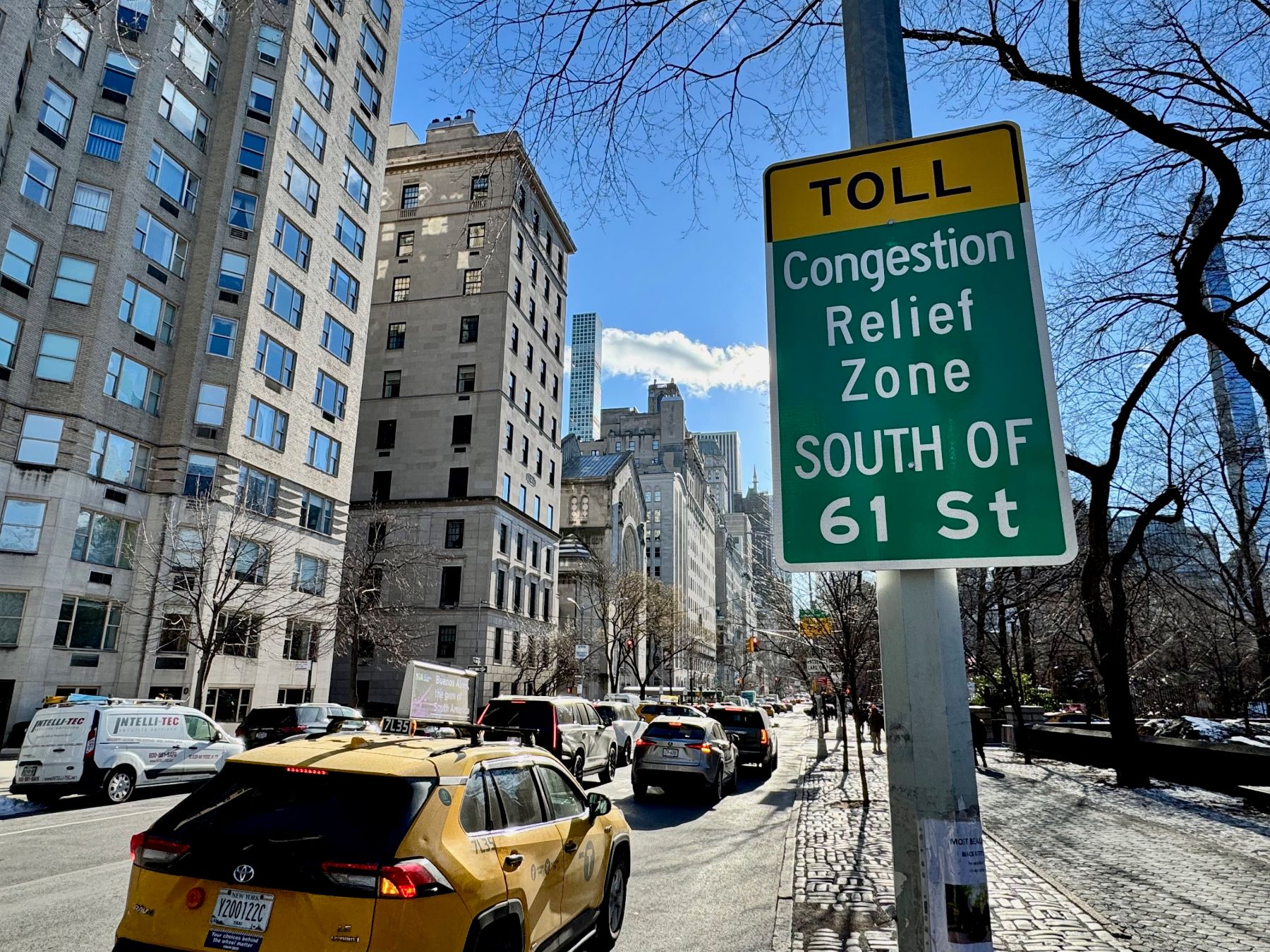 Cars driving next to a sign that says 'Toll. Congestion Relief Zone'