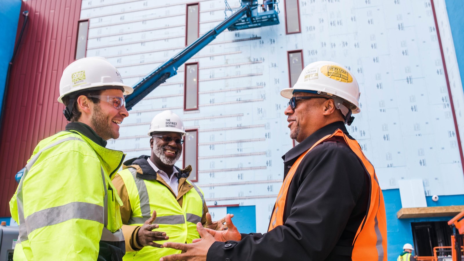 Men in safety gear speaking on a construction site.